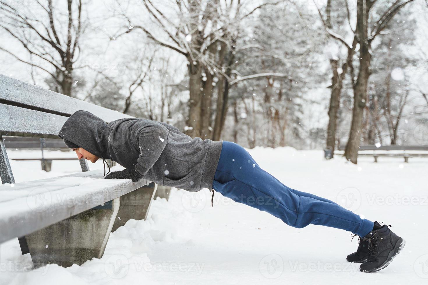 Athletic man doing push-ups during his calisthenics winter workout photo