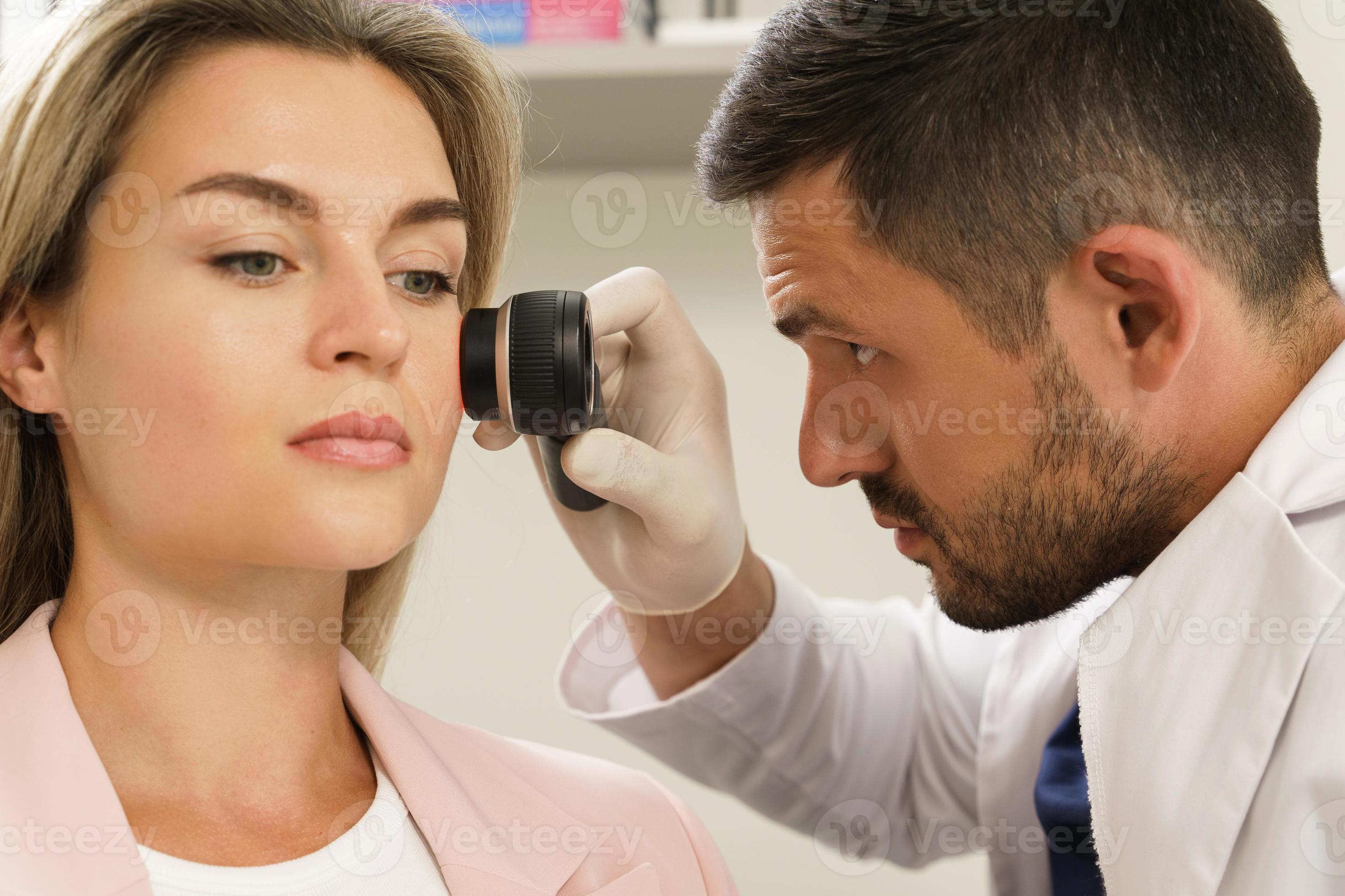 Dermatologist is using dermatoscope for facial skin examination