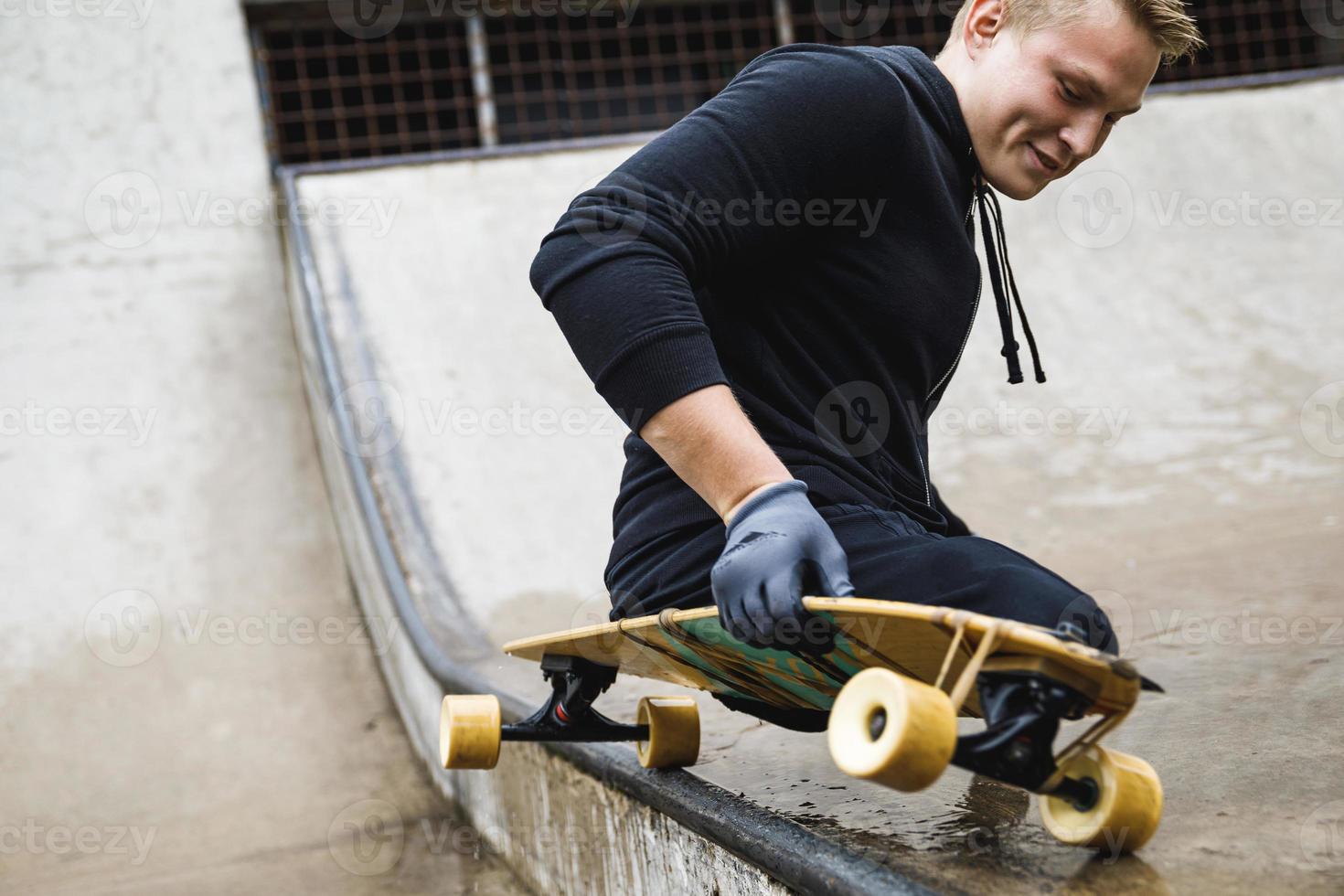Motivated handicapped guy with a longboard in the skatepark photo
