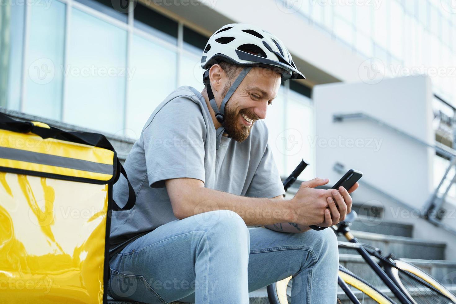 Express food delivery courier sitting on the stairs with insulated bag and bicycle. photo