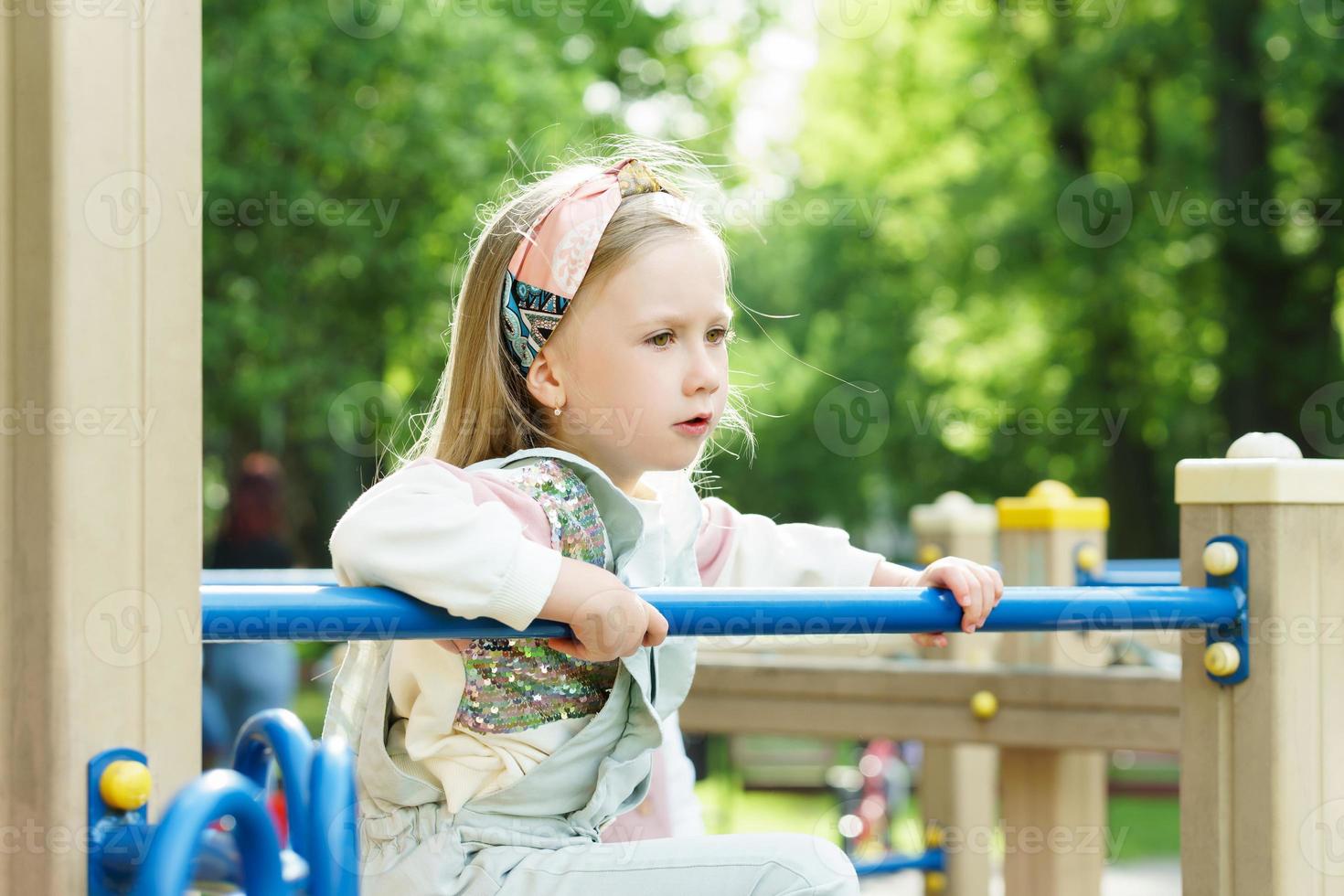 Cute little girl playing on a playground in a city park photo