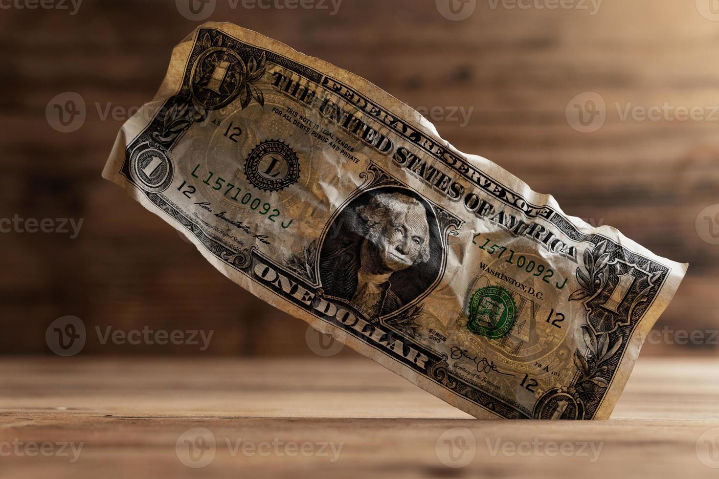 Closeup shot of a crumpled one dollar bill stuck in a gap in the floor. photo