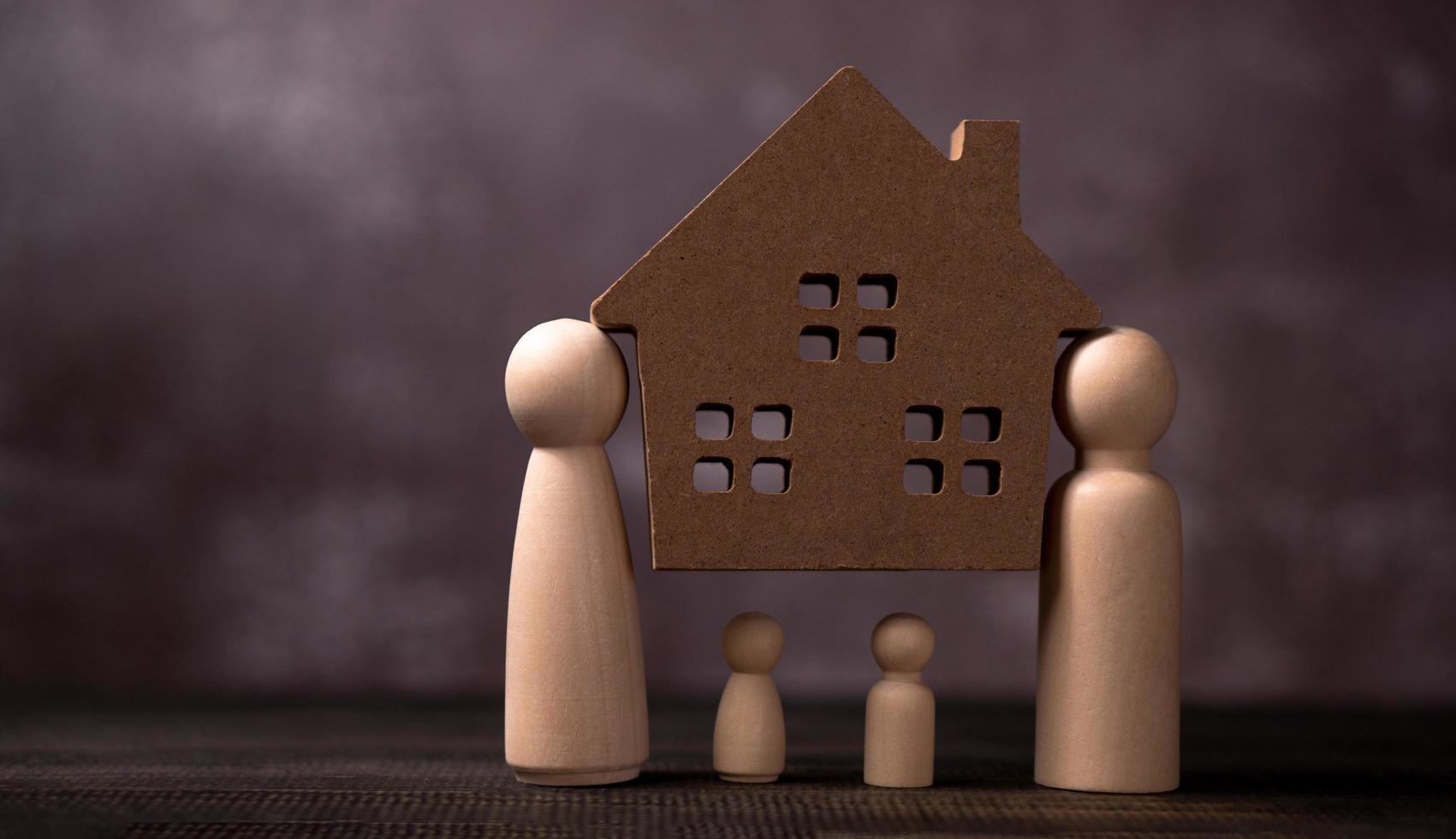 figuras de madera familia de pie y oso casa de madera para proteger y cargar los problemas para proteger a la familia. el concepto de protección y seguridad, seguridad en el hogar, seguro de propiedad y casa. foto