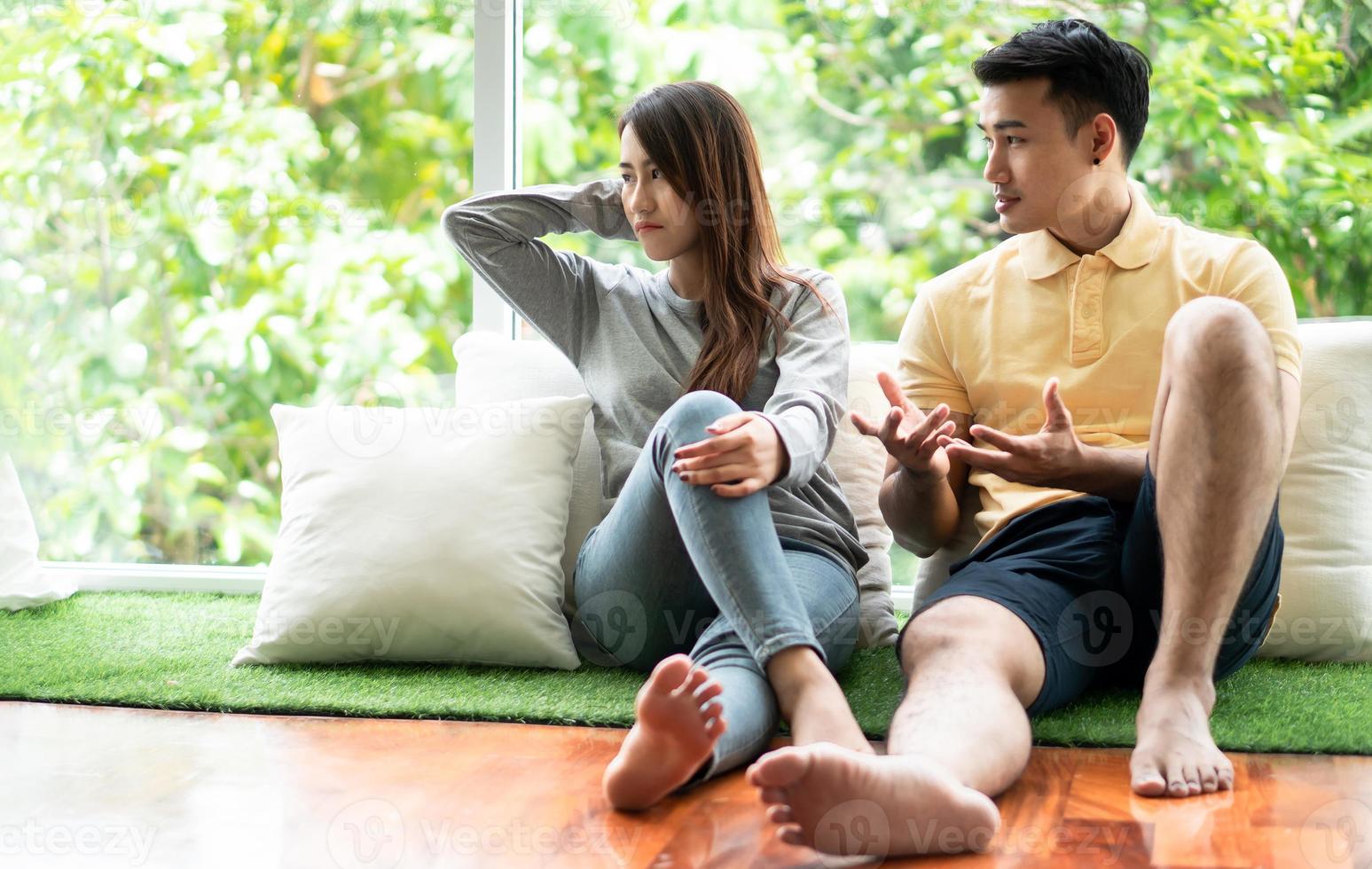 una pareja infeliz sentada una al lado de la otra en el suelo y evita hablar o pelear, causa de problemas de relación y malentendidos o desacuerdos. concepto de problemas familiares foto