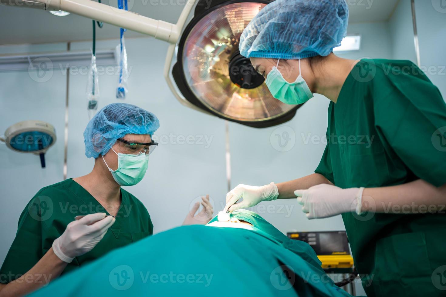 equipo de cirujanos profesionales asiáticos que realizan cirugía en el quirófano, cirujano, asistentes y enfermeras que realizan cirugía en un paciente, cáncer de atención médica y concepto de tratamiento de enfermedades foto