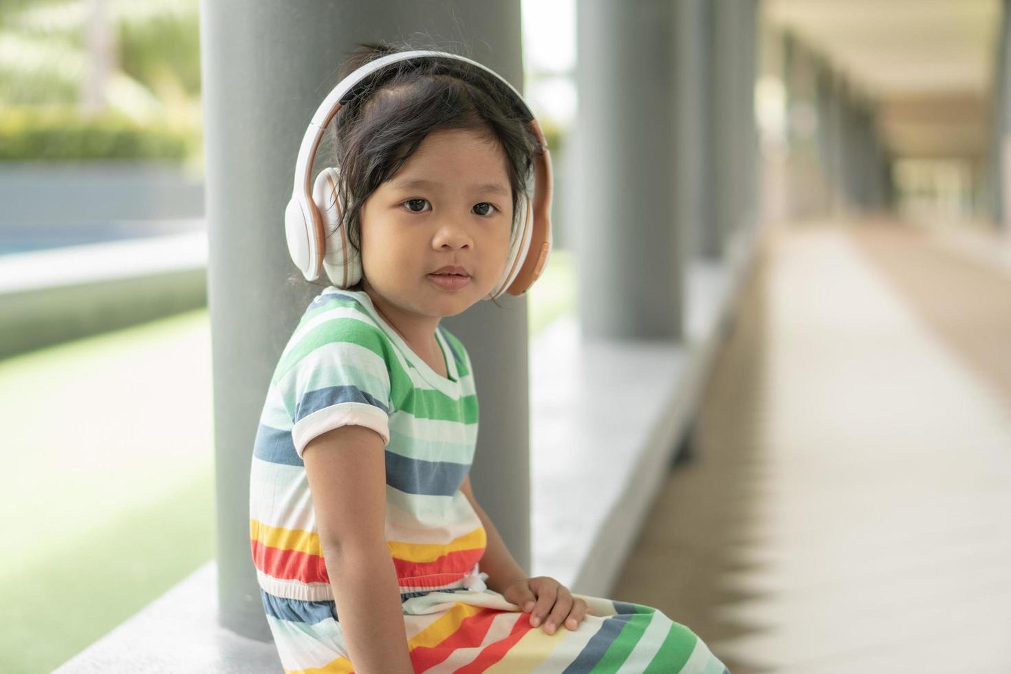 niña encantadora muy agradable y escuchando música con auriculares y estaba cómodamente sentada foto