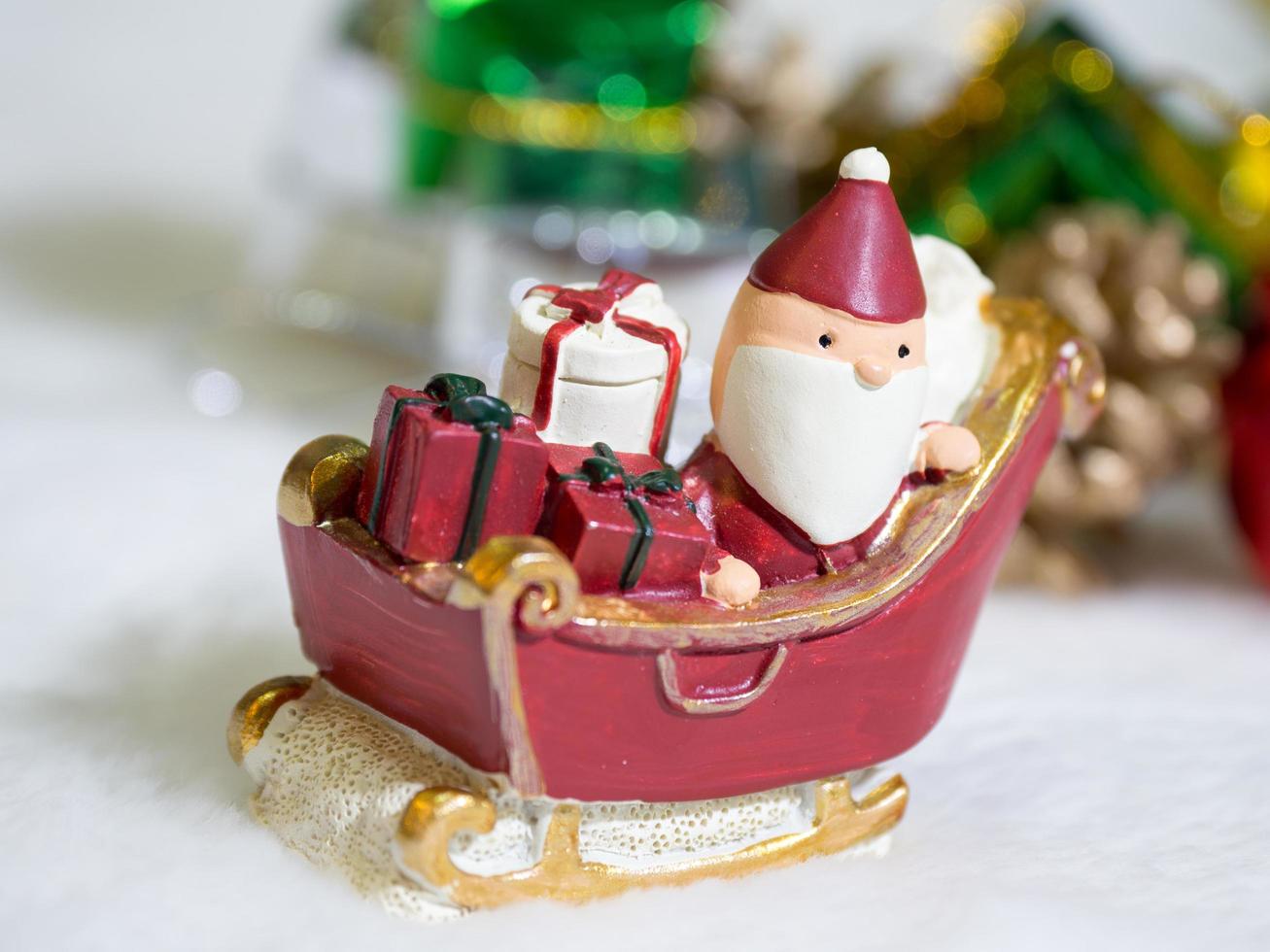 feliz santa claus con caja de regalos en el trineo de nieve el fondo es decoración navideña.santa claus y decoración navideña en la nieve. feliz navidad y feliz año nuevo concepto foto