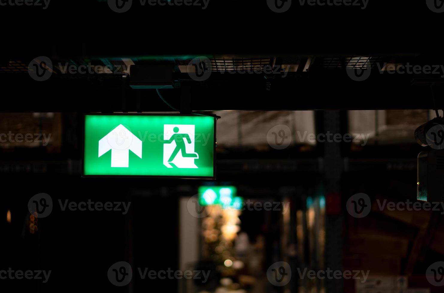 Green fire escape sign hang on the ceiling in the Warehouse. The concept of fire escape training and preparation for evacuation photo