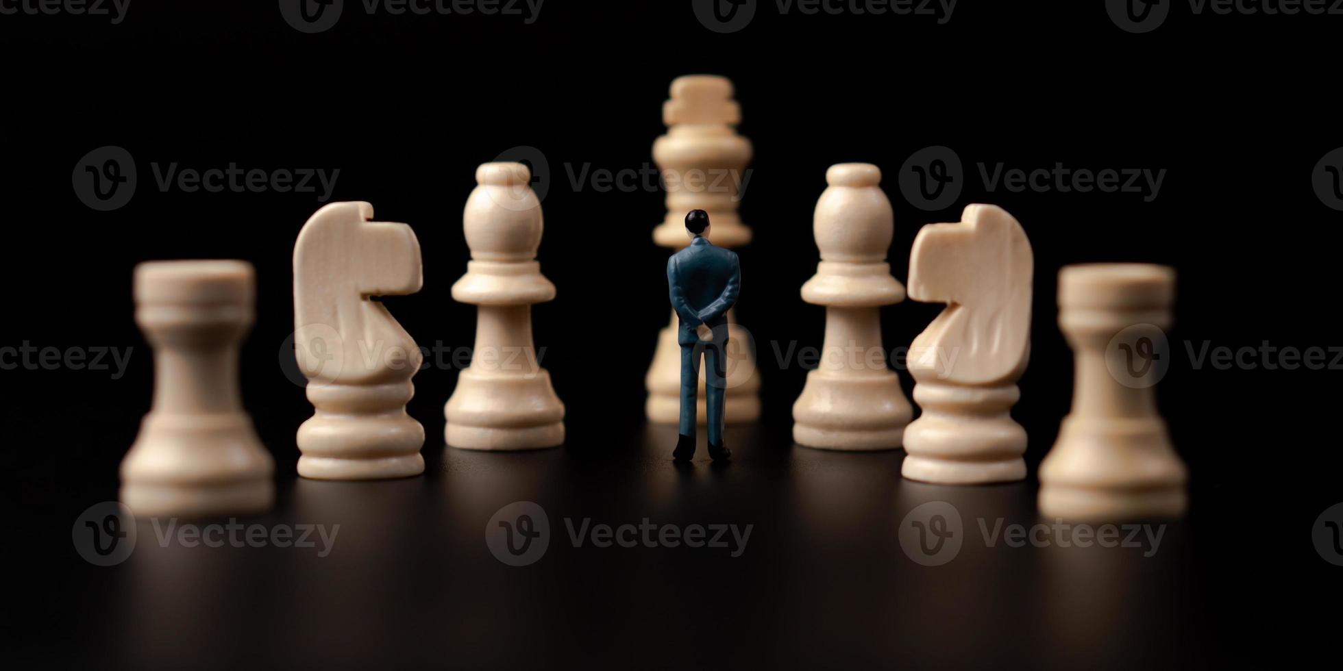 Figures businessman standing in front of wooden chess on black isolated background. Concept of business analysis and strategy. Stepping into the startup, new business player photo