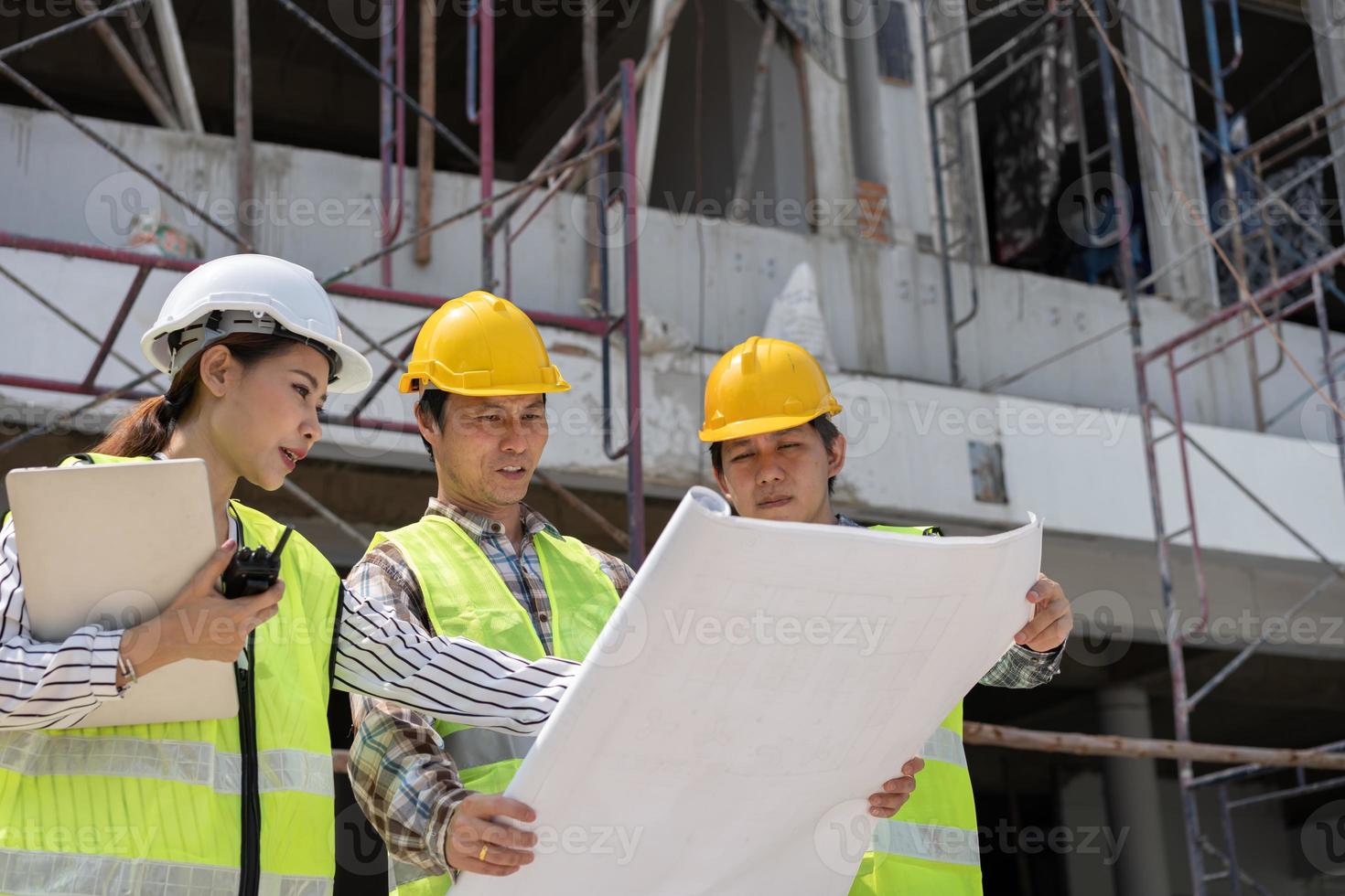 Asian engineer or Young Female Architect put on a helmet for safety and talk with a contractor on a construction building factory project, Concept of Teamwork, Leadership concept. photo