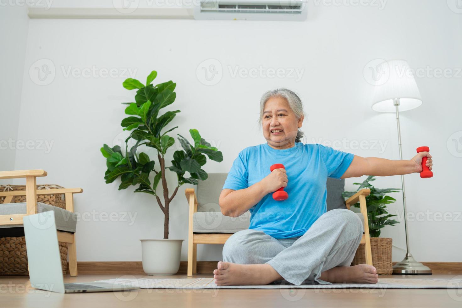 anciana asiática levantando pesas para hacer ejercicio y hacer ejercicio en casa. mujer madura activa haciendo ejercicio de estiramiento en la sala de estar. ejercicio activo y saludable para personas mayores, mayores y mayores. foto