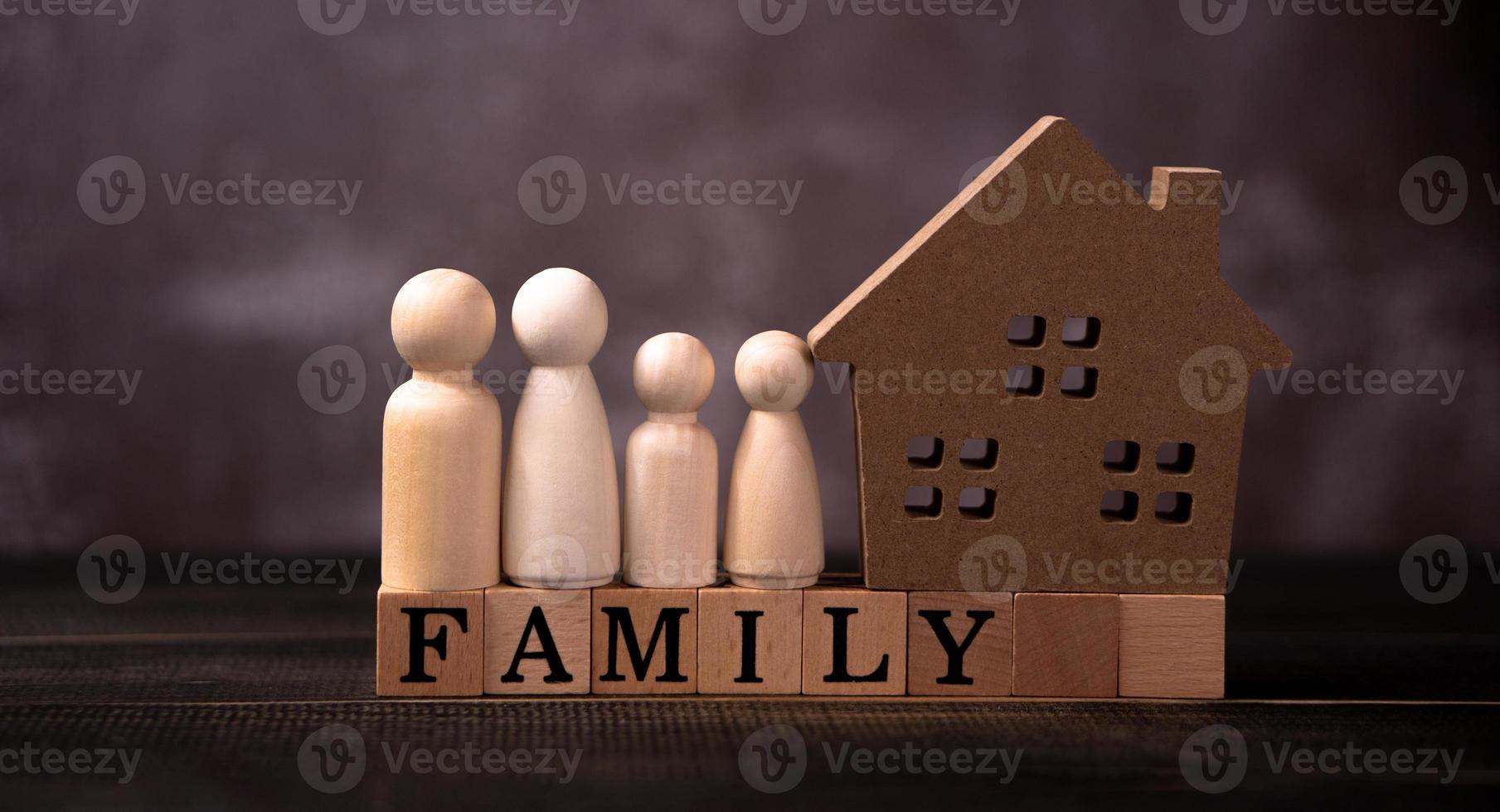 figuras de madera familia de pie junto a una casa de madera en un cubo de madera que escribe la palabra familia. el concepto de protección y seguridad, seguridad en el hogar, seguro de propiedad y casa. foto