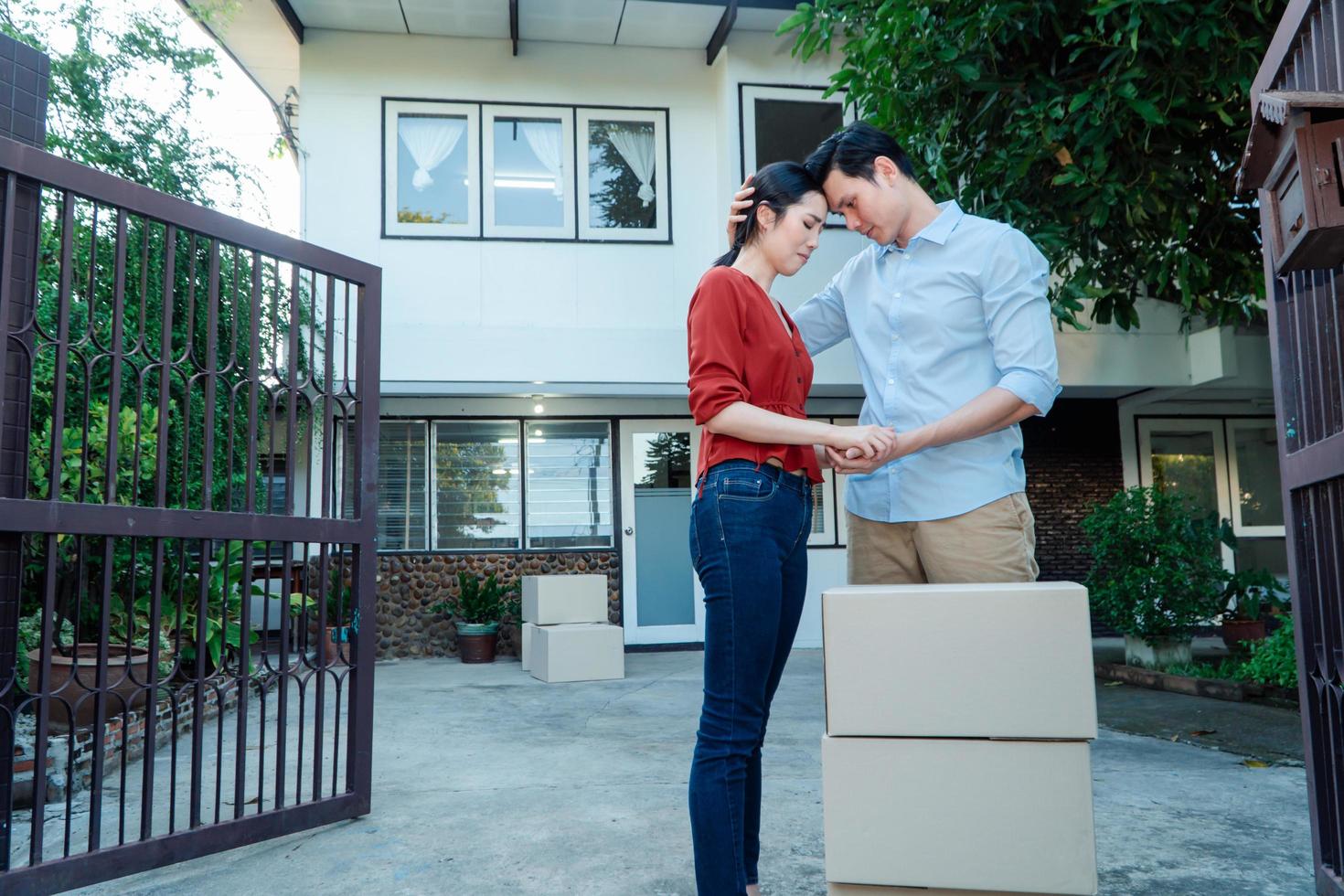 hombre consolando a su esposa y mujer abrazando a su esposo y llorando frente a la casa y llenos de cajas de cartón durante el transporte en el día de la mudanza, concepto de mudanza a casa foto