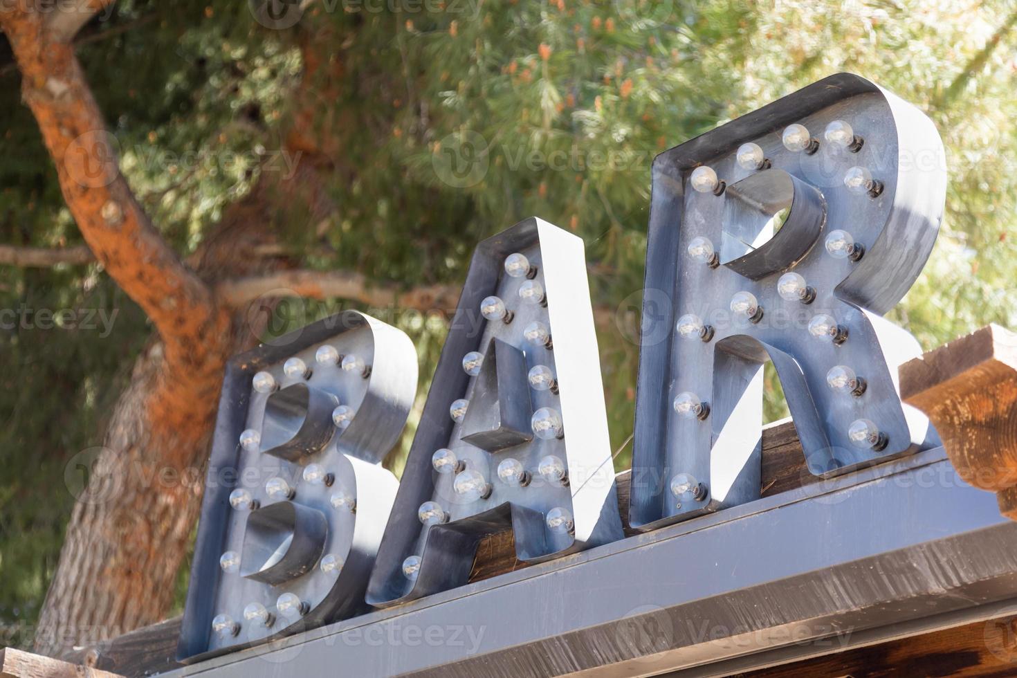 Industrial Marquee letters Bar Sign with Bulbs on Roof of Business. photo