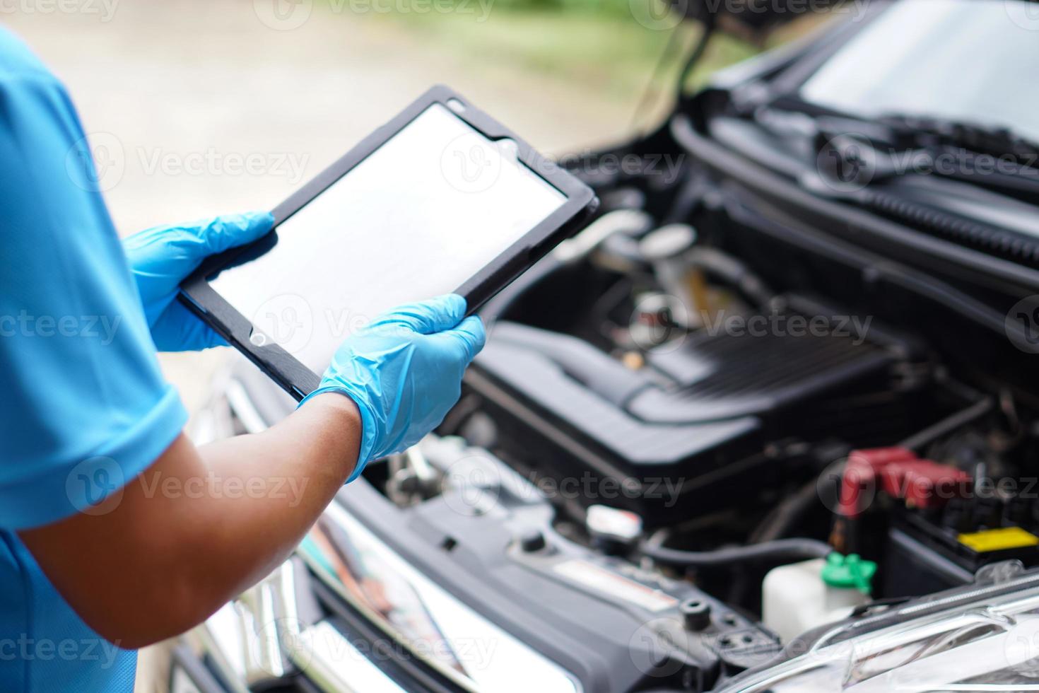 Mechanic is checking car engine, use smart tablet to record and diagnose the problems of engine . Concept ,using technology to manage car engine. Car service and maintenance. photo