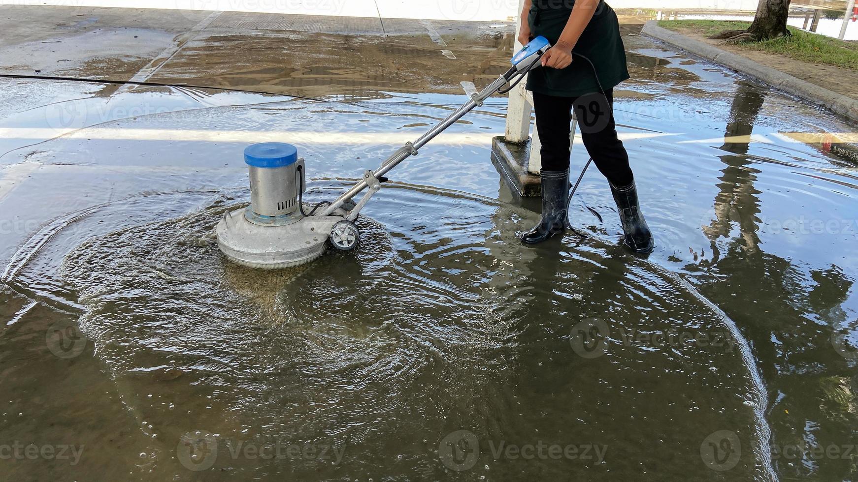 Employees use a concrete floor scrubber in the office parking lot. home or hotel Clean the exterior floor with a scrubber and chemical solution. commercial business services photo