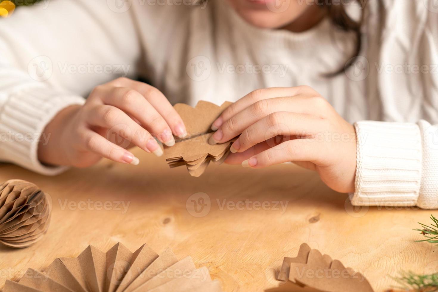girl makes Christmas tree decorations out of paper with her own hands. step-by-step instruction photo