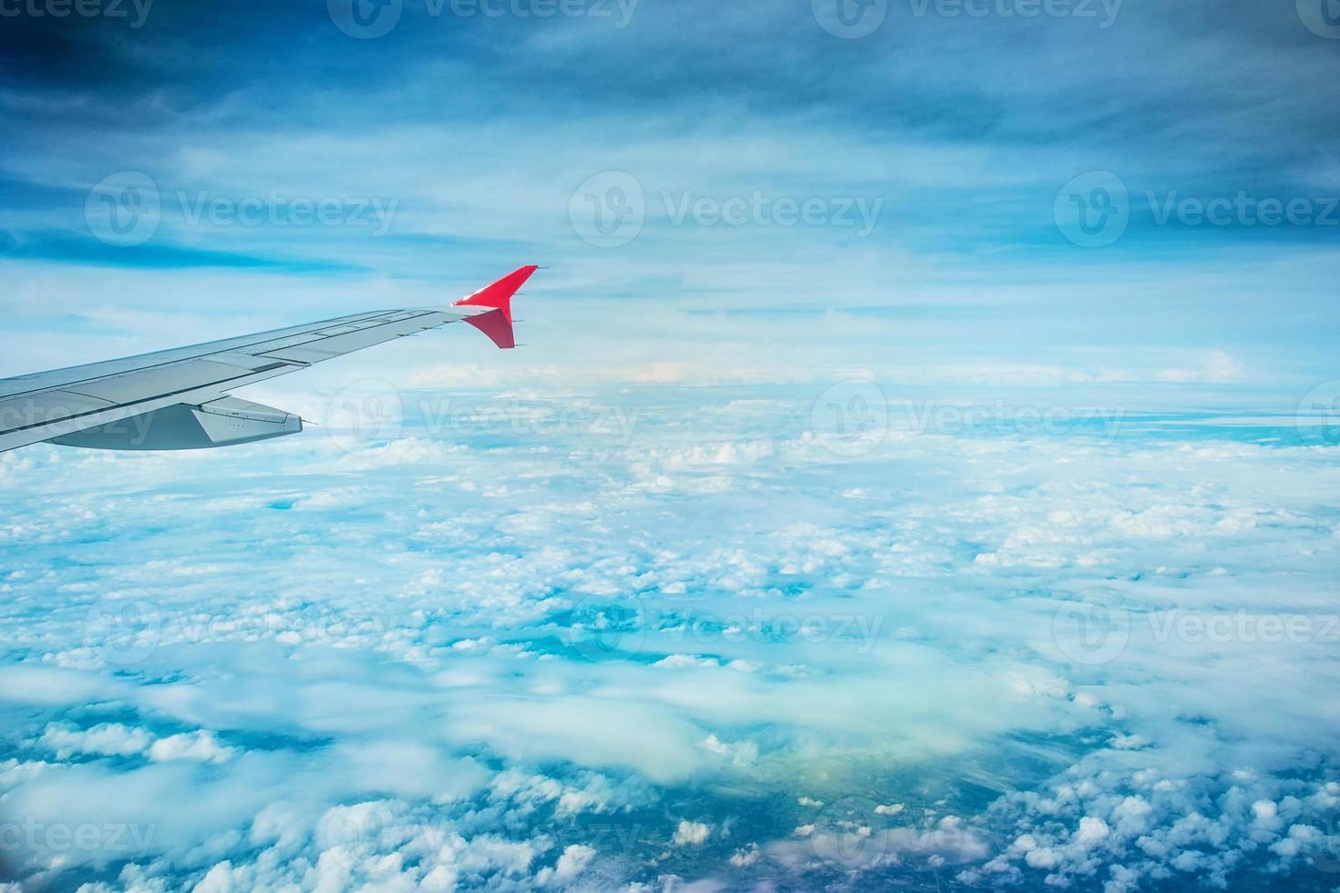 Wing of an airplane flying above white clouds. photo