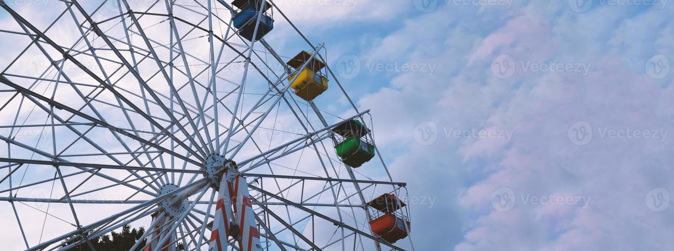 Colorful ferris wheels in the amusement park on a background of blue sky with clouds. Toned image. Bottom view photo