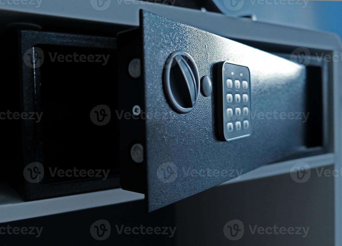 Metal safe box in the closet. Small narrow safe for keeping money or valuables in the hotel. Open safe door with buttons for entering a password. Compact strongbox inside cabinet. Empty safe. photo