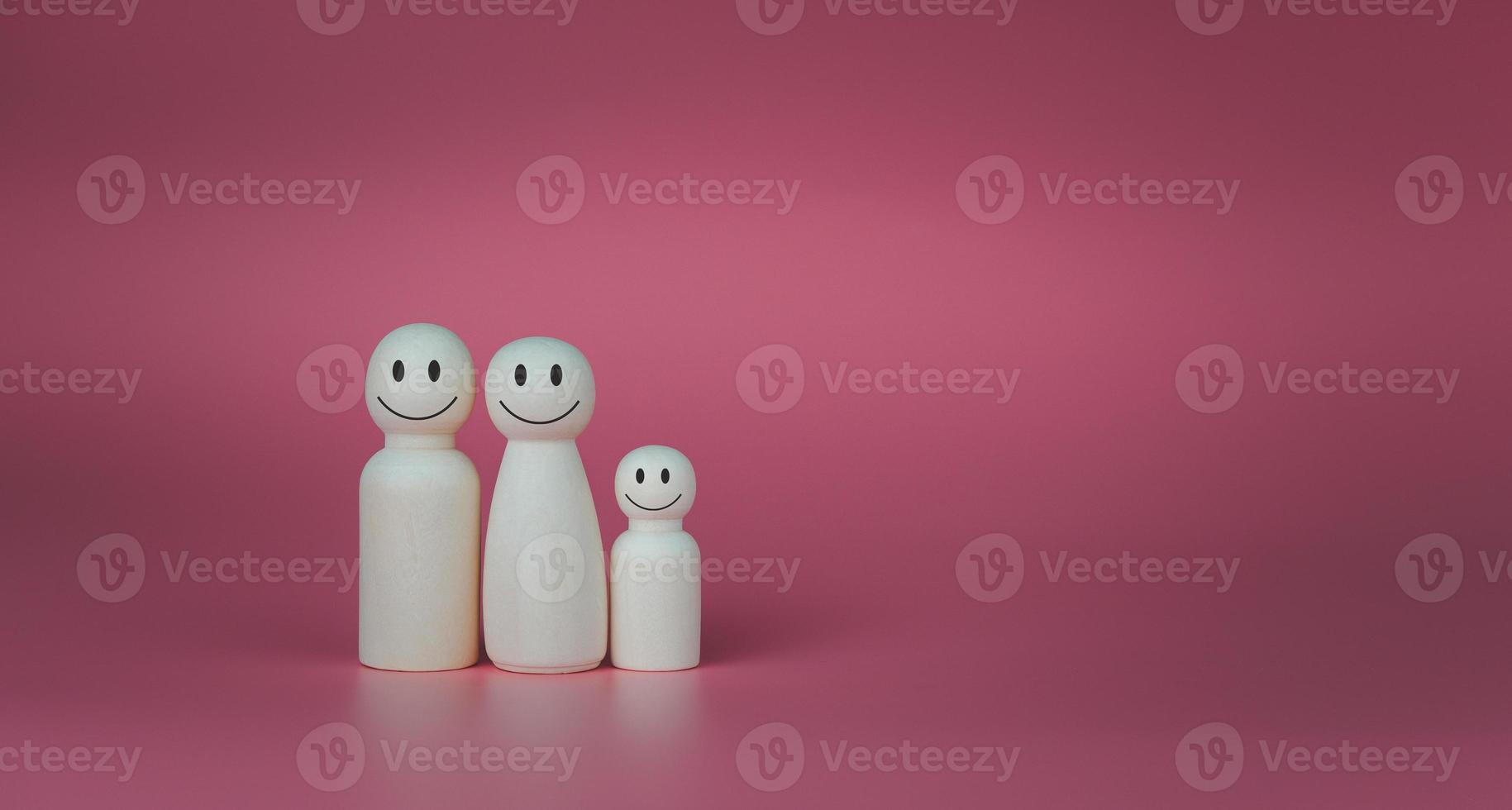 Happy house concept. Wooden dolls stand lined up against a pink background. Indicates happiness and love in the house. photo