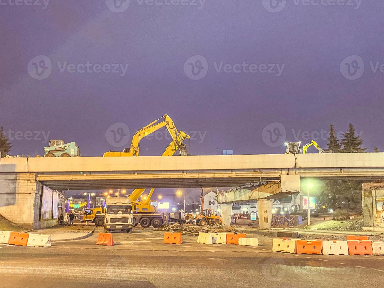 construcción de un puente en el centro de la ciudad. el camino está cercado con elementos de protección de los automóviles. paso elevado en construcción en la ciudad por la noche foto