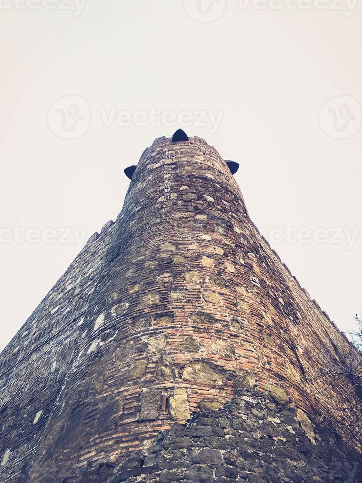 Beautiful vintage ancient old stone medieval authentic high protective tower of cobblestones against a blue sky photo