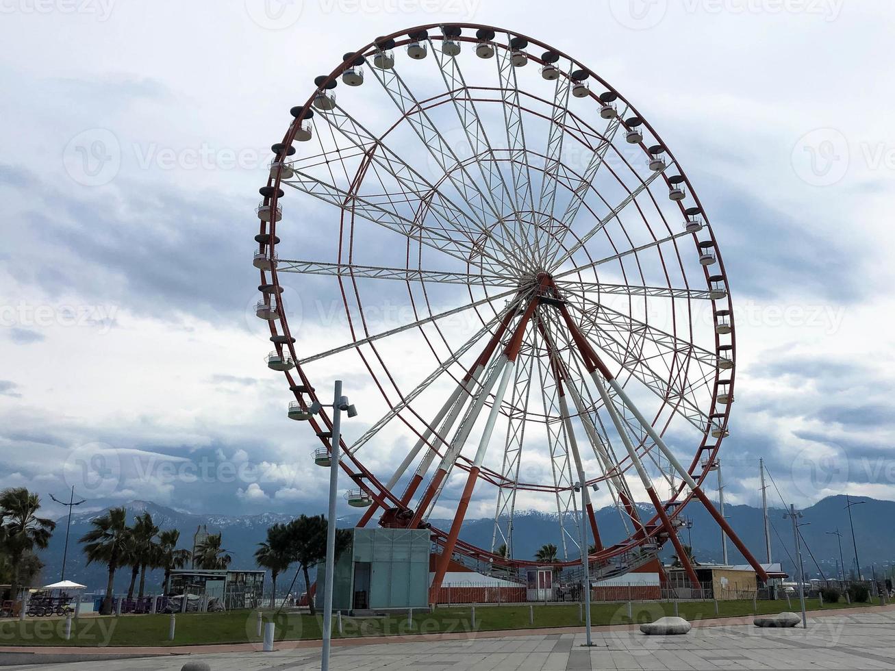 A large round beautiful Ferris wheel, a panoramic platform in a park on a tropical sea warm summer resort with palm trees against a blue sky photo