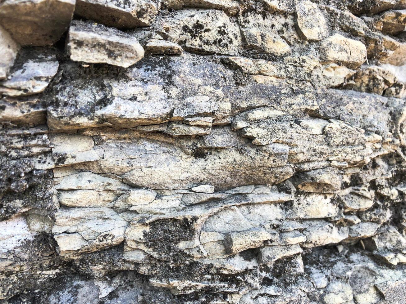 The texture of the stone wall of sharp cracked convex rough natural gray puff of old ancient stone bricks in the rock. The background photo