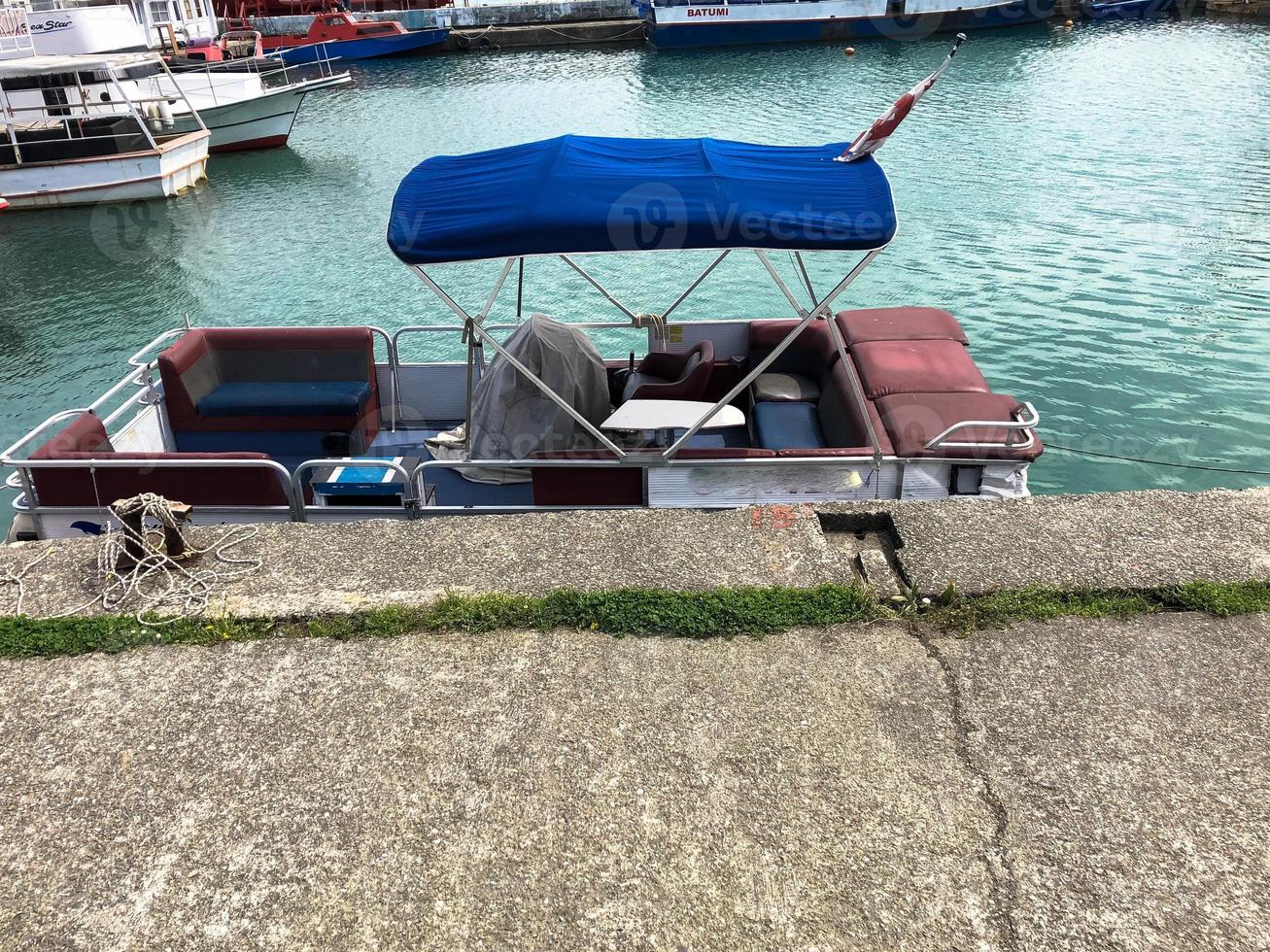 A small boat with a stretch canvas roof stands on the quay at the port on the water in the sea photo