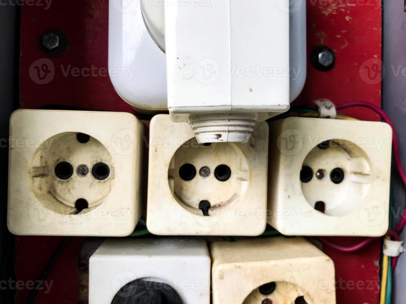 texture with white rosettes. electrical panel with several white sockets. sockets on a red background. homemade electrical panel with your own hands. construction of a house and communications photo