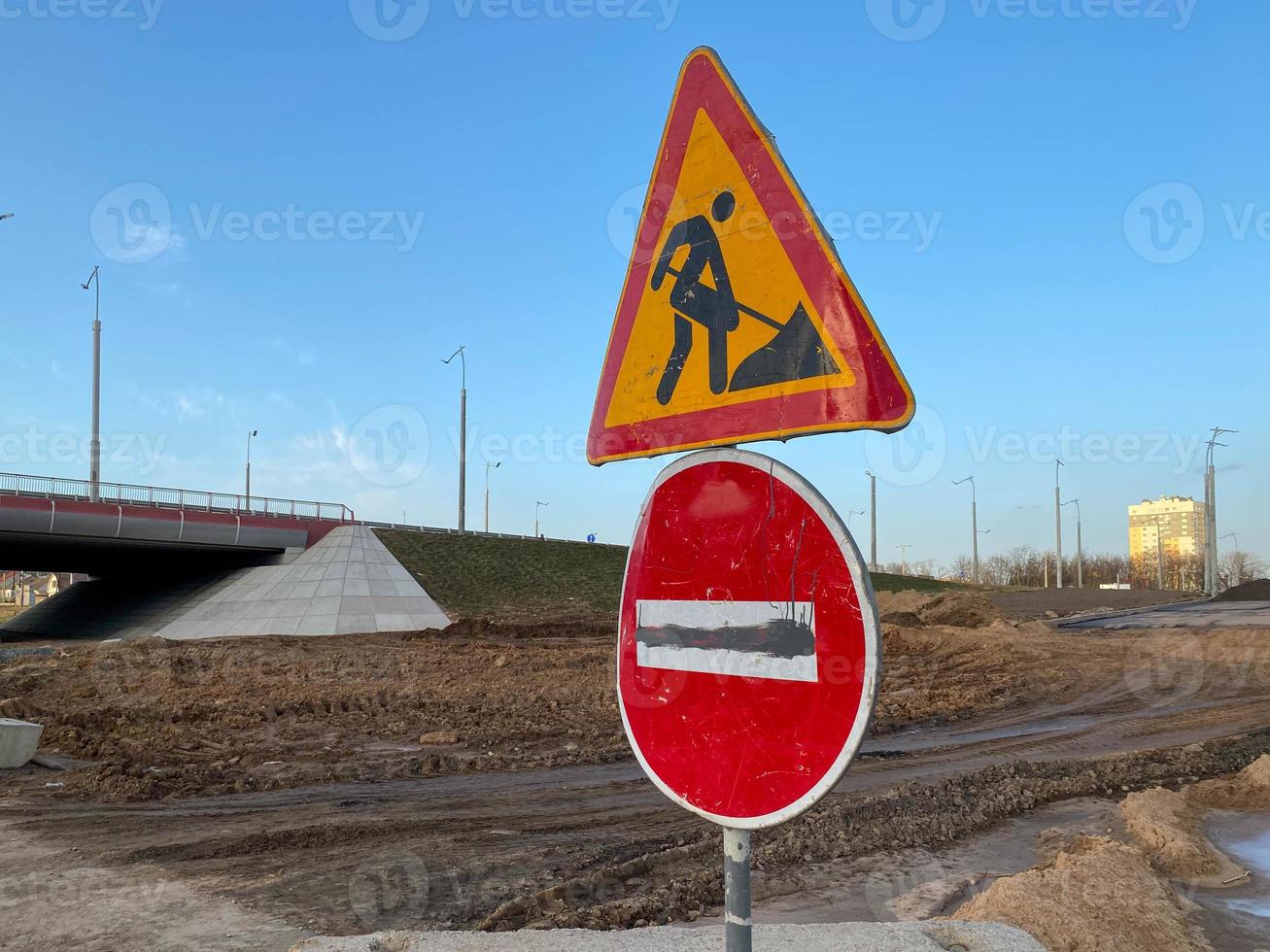 bajo el letrero del tablero de construcción en la carretera cerrada con señal de flecha y cono de tráfico. símbolo de precaución en construcción, signo de trabajo en progreso foto