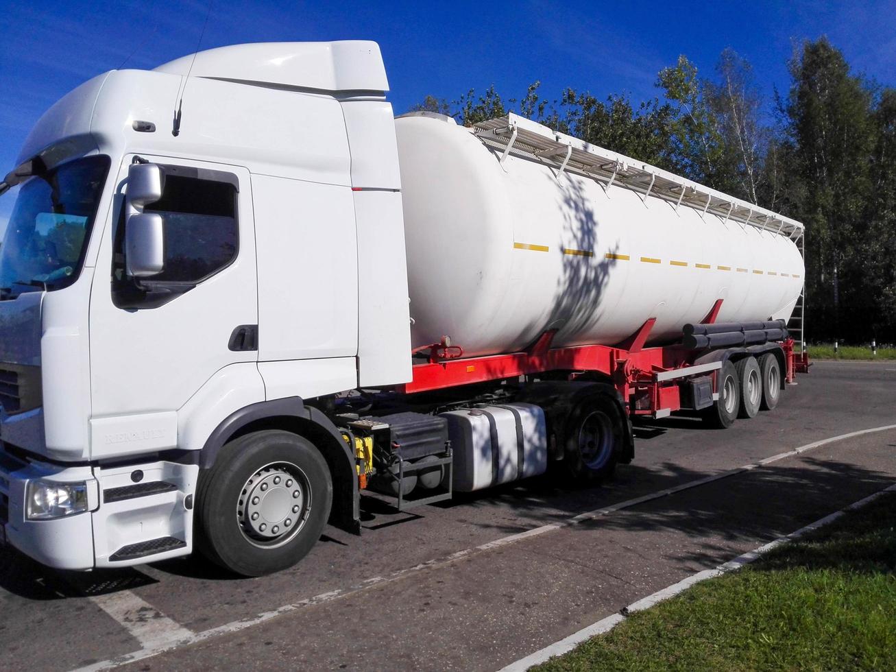 Large white lorry with a tank container for liquid or gaseous dangerous goods photo