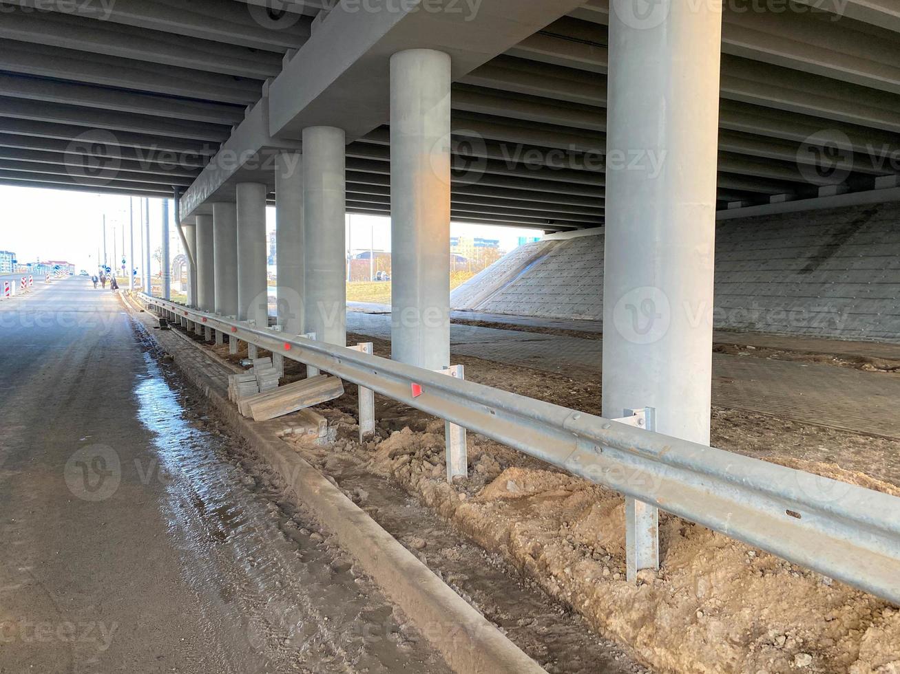 trabajo industrial de construcción bajo un puente con columnas y parachoques y un gran paso elevado de automóviles foto