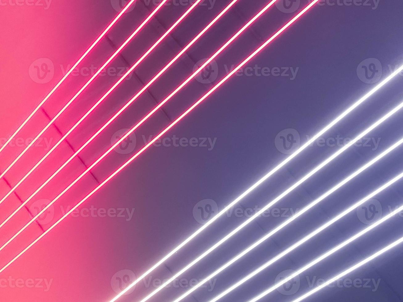 Texture of purple, pink and white glowing bright neon LED multicolored laser abstract stripes and lines from parallel lamps. The background photo
