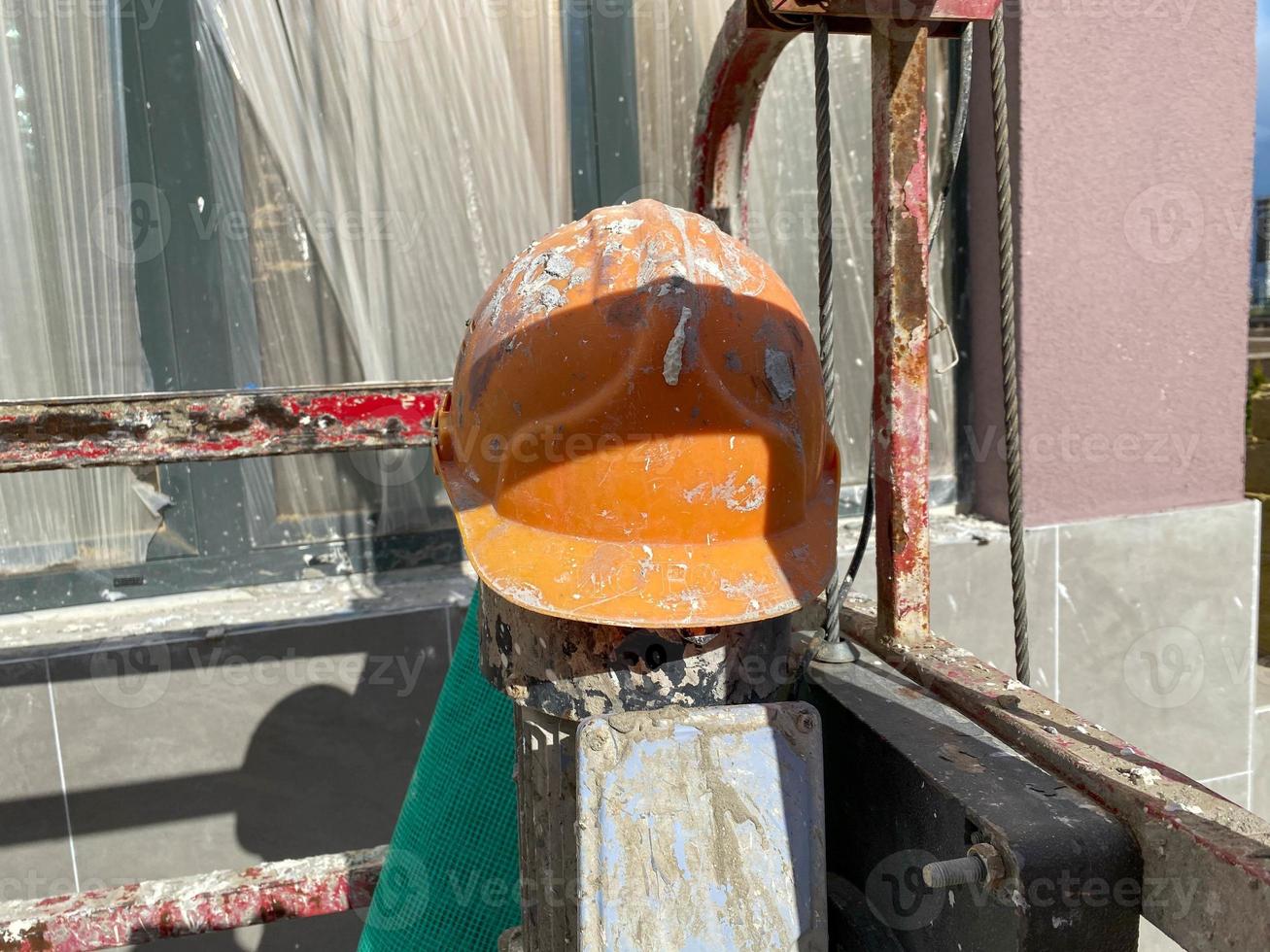 Yellow plastic protective dirty scratched old construction worker's helmet to protect head from falling objects at construction site photo