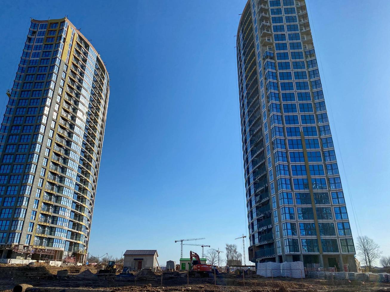 dos altos y hermosos edificios modernos sin terminar hechos de vidrio y hormigón contra un cielo azul foto