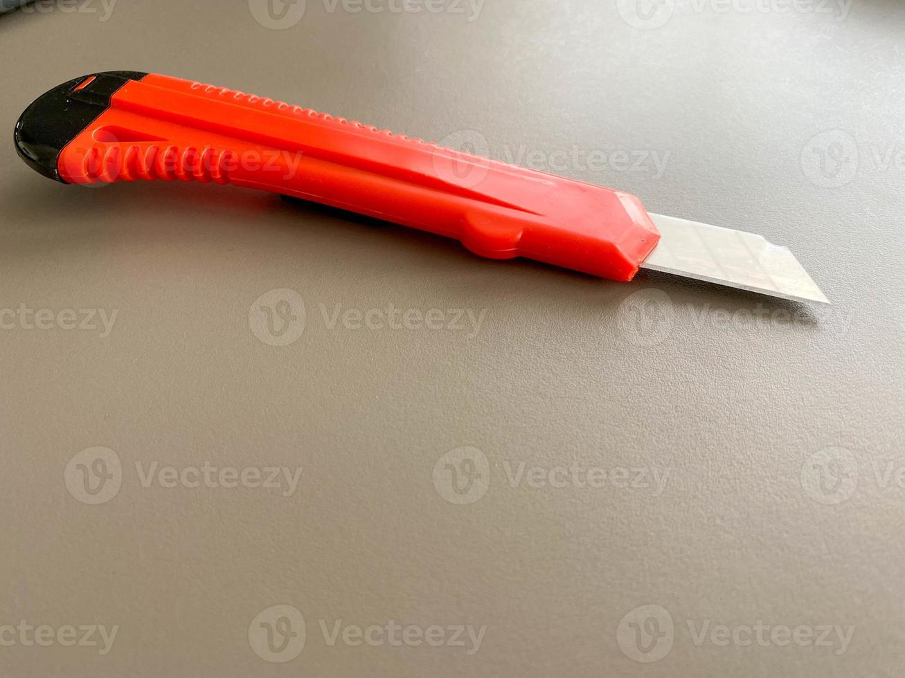 Red sharp office stationery knife with a paper cutting blade on a desktop office desk. Business work photo