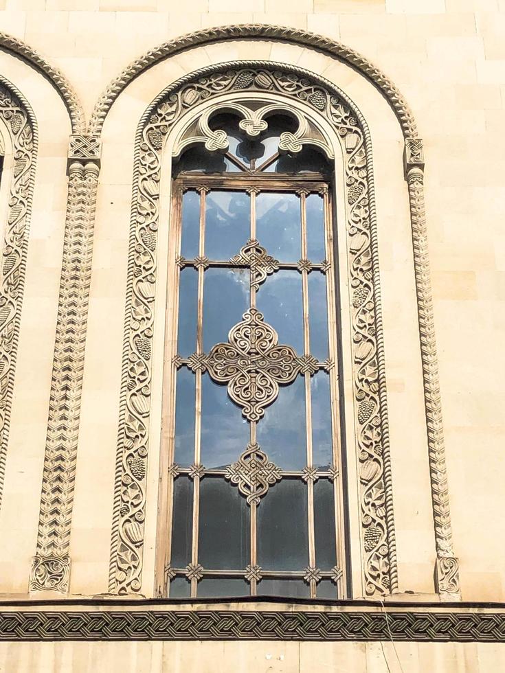 Beautiful vintage ancient old carved window with glass with a forged frame arches and patterns. The background photo