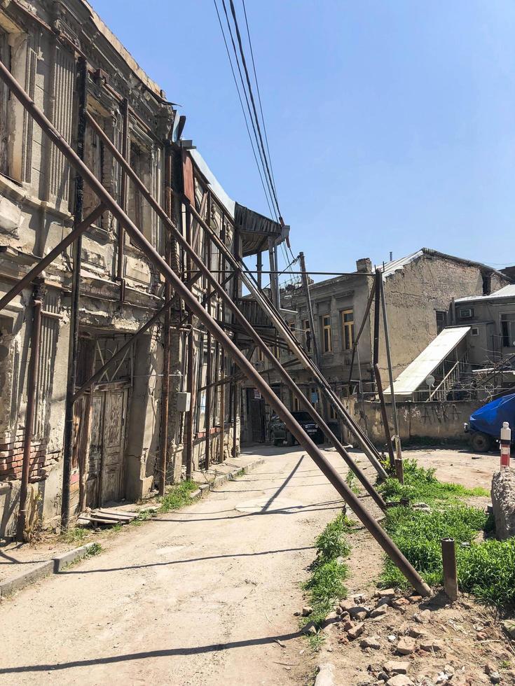 Iron pillars, piles propped up, keep leaning down falling old dangerous dilapidated collapsing house building. Unusual funny architecture photo