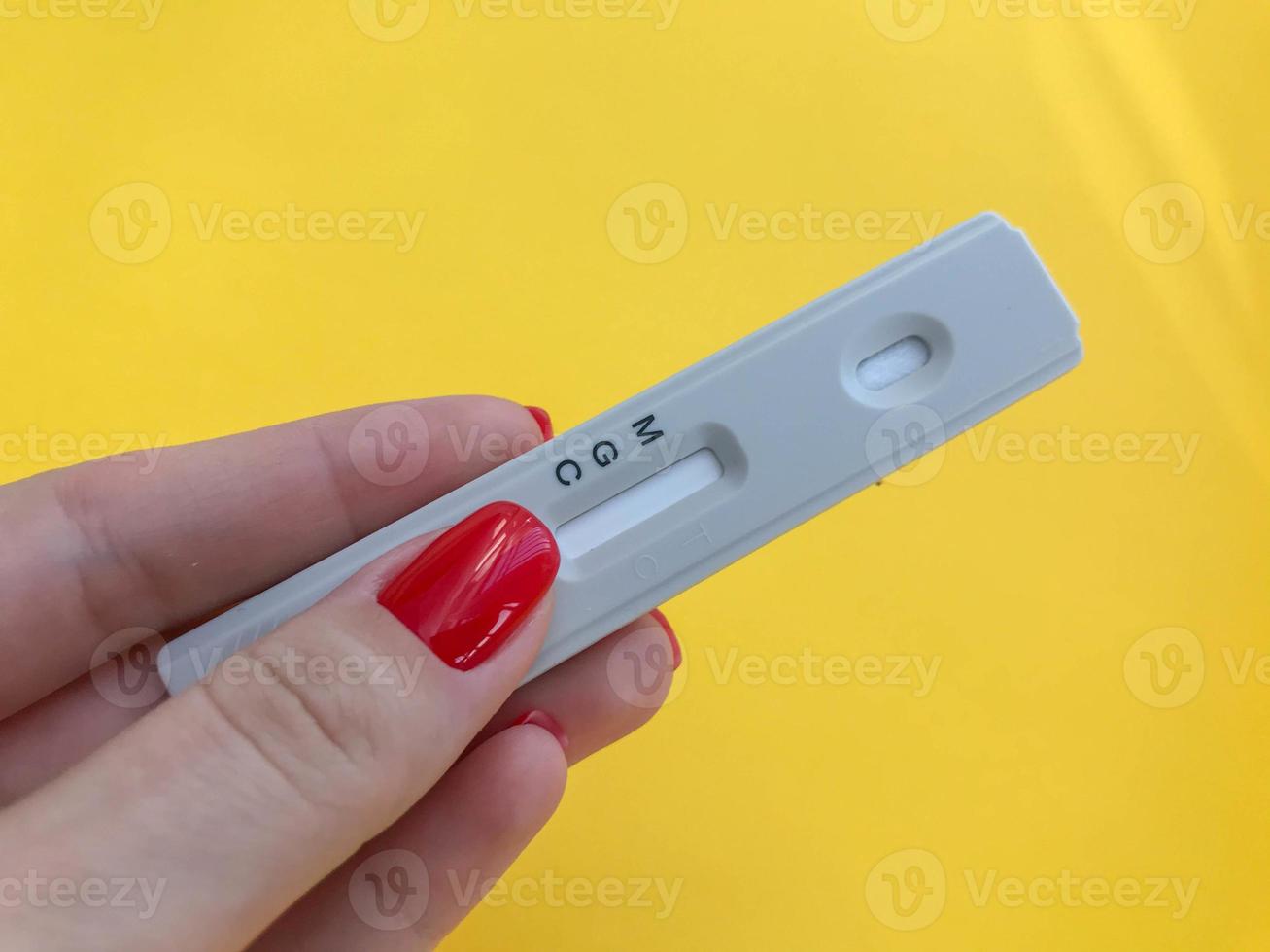 medical procedures. coronavirus test on a bright yellow background. girl with bright red manicure holds a strip. IgG and IgM antibodies test photo