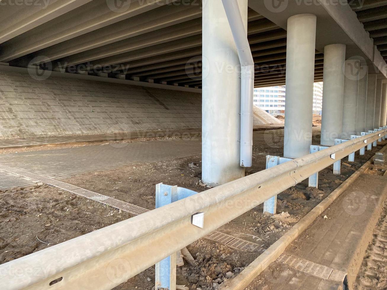 Construction industrial work under a bridge with columns and bumpers and a large car overpass road photo