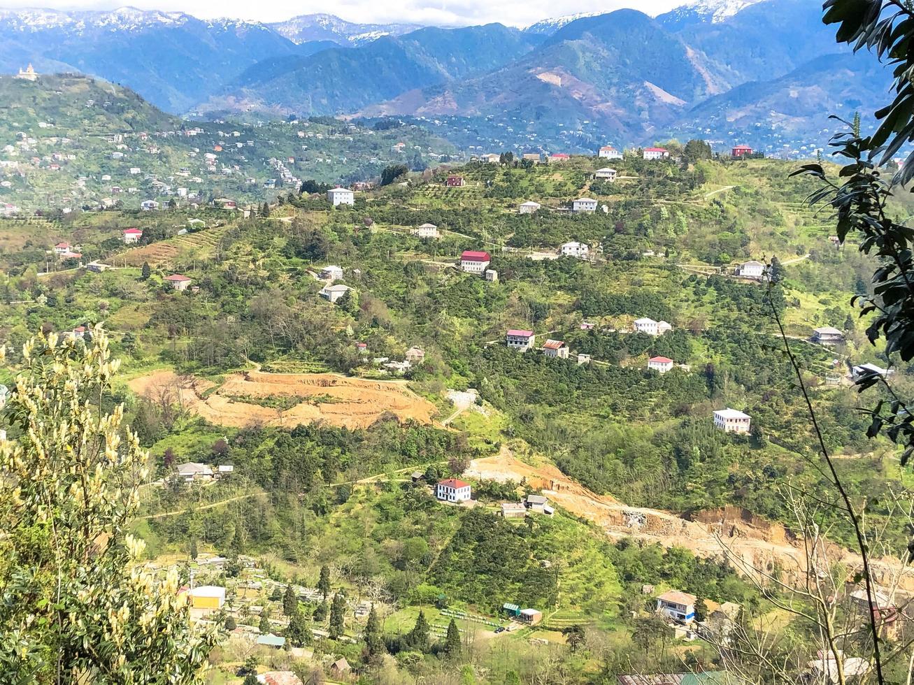 The view from the top from a height of a beautiful tourist city with buildings and houses, roofs of trees and plants, nature against a blue sky and mountains. European old architecture photo