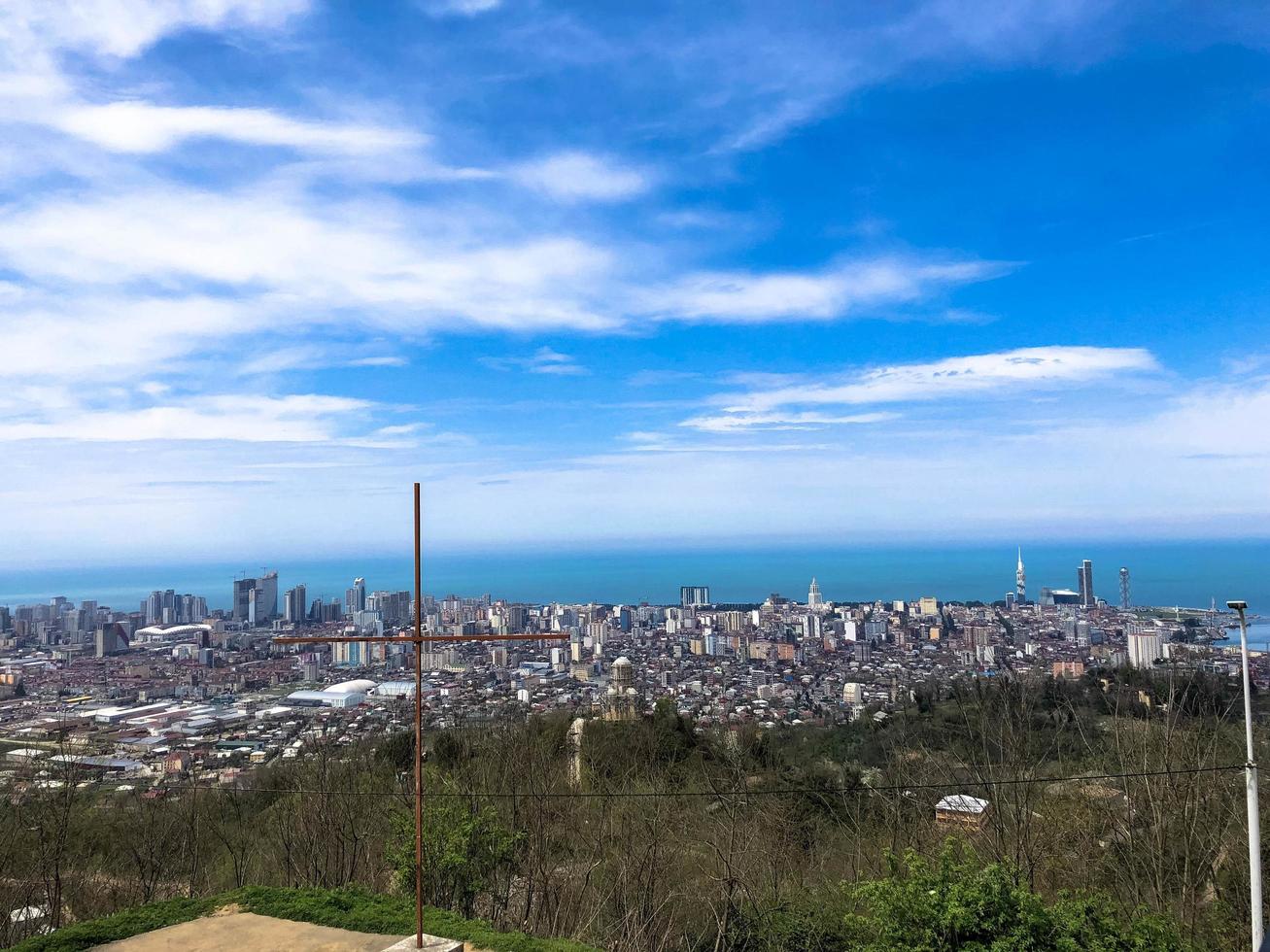The view from the top from a height of a beautiful tourist city with buildings and houses, roofs of trees and plants, nature against a blue sky and mountains. European old architecture photo