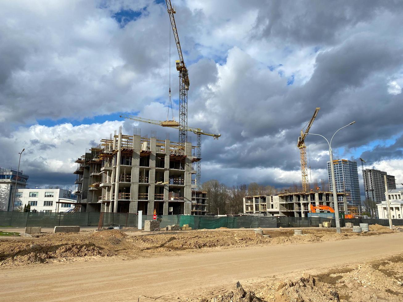 un nuevo edificio grande, alto e inacabado que se está construyendo con la ayuda de una grúa torre industrial de construcción de gran altura foto