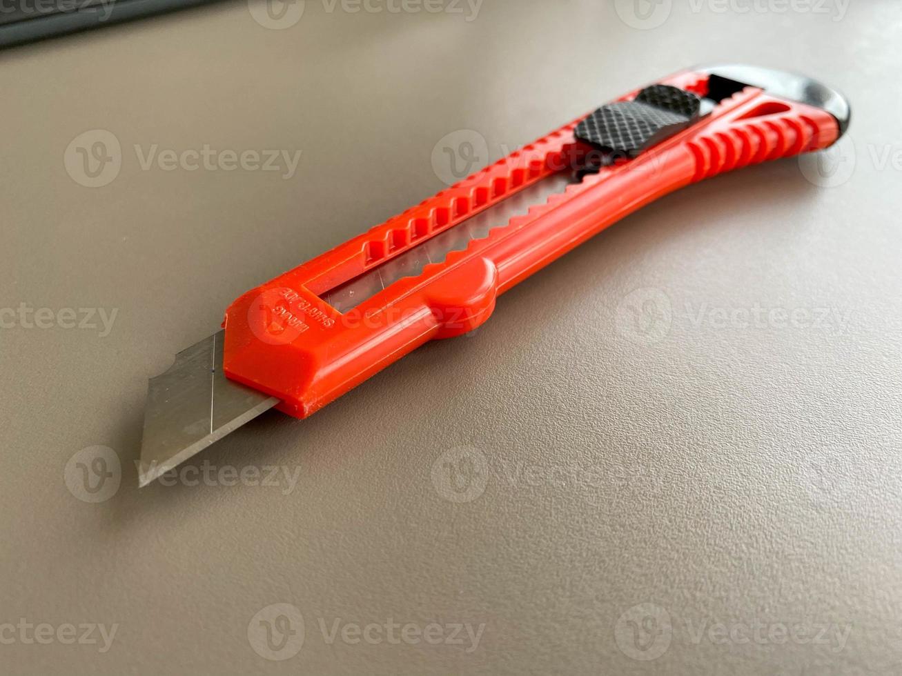 cuchillo de papelería de oficina afilado rojo con una hoja de corte de papel en un escritorio de oficina. trabajo de negocios foto