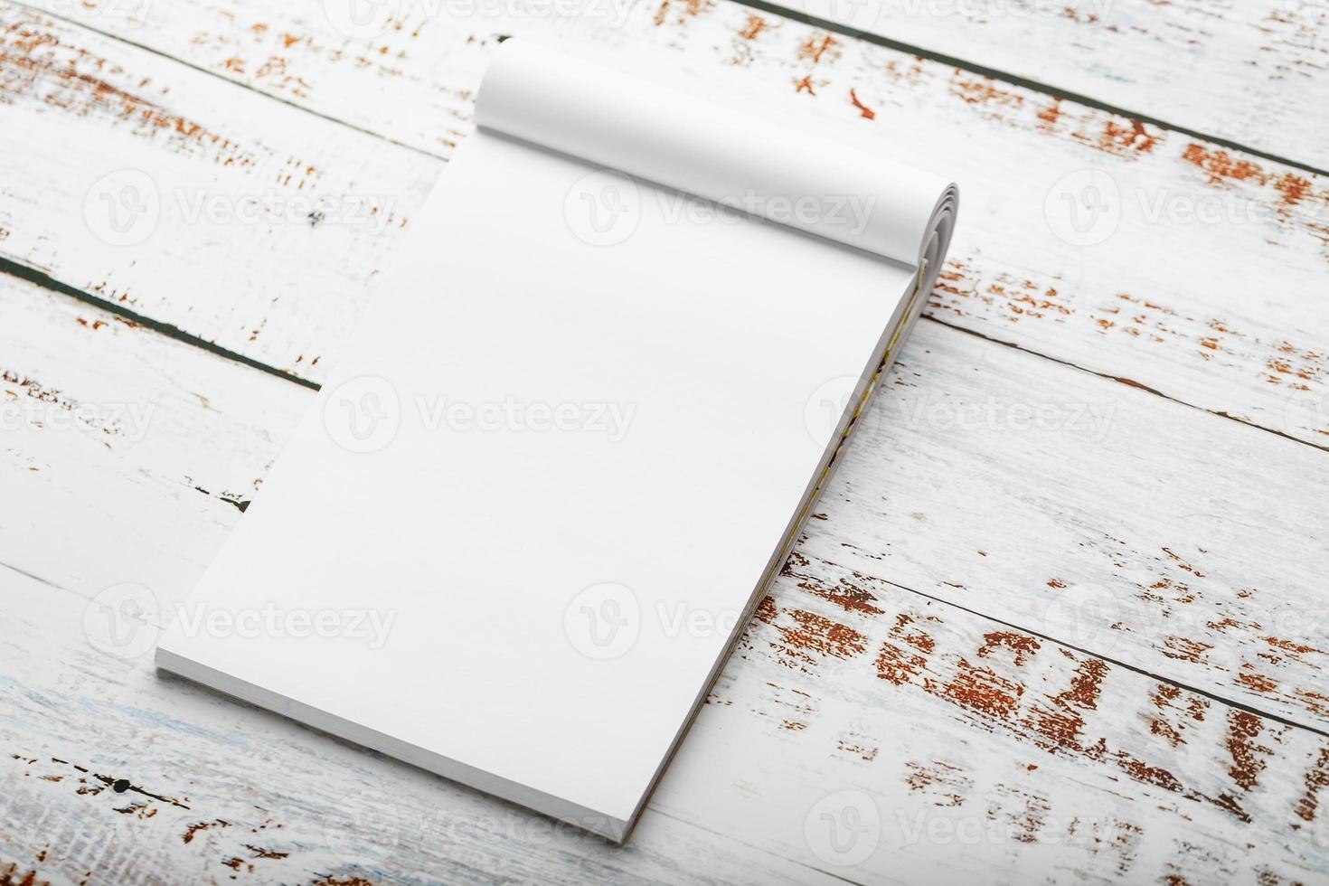 bloc de notas con un lápiz rojo sobre una mesa de madera blanca en el fondo, para educación, registro de objetivos y hechos foto
