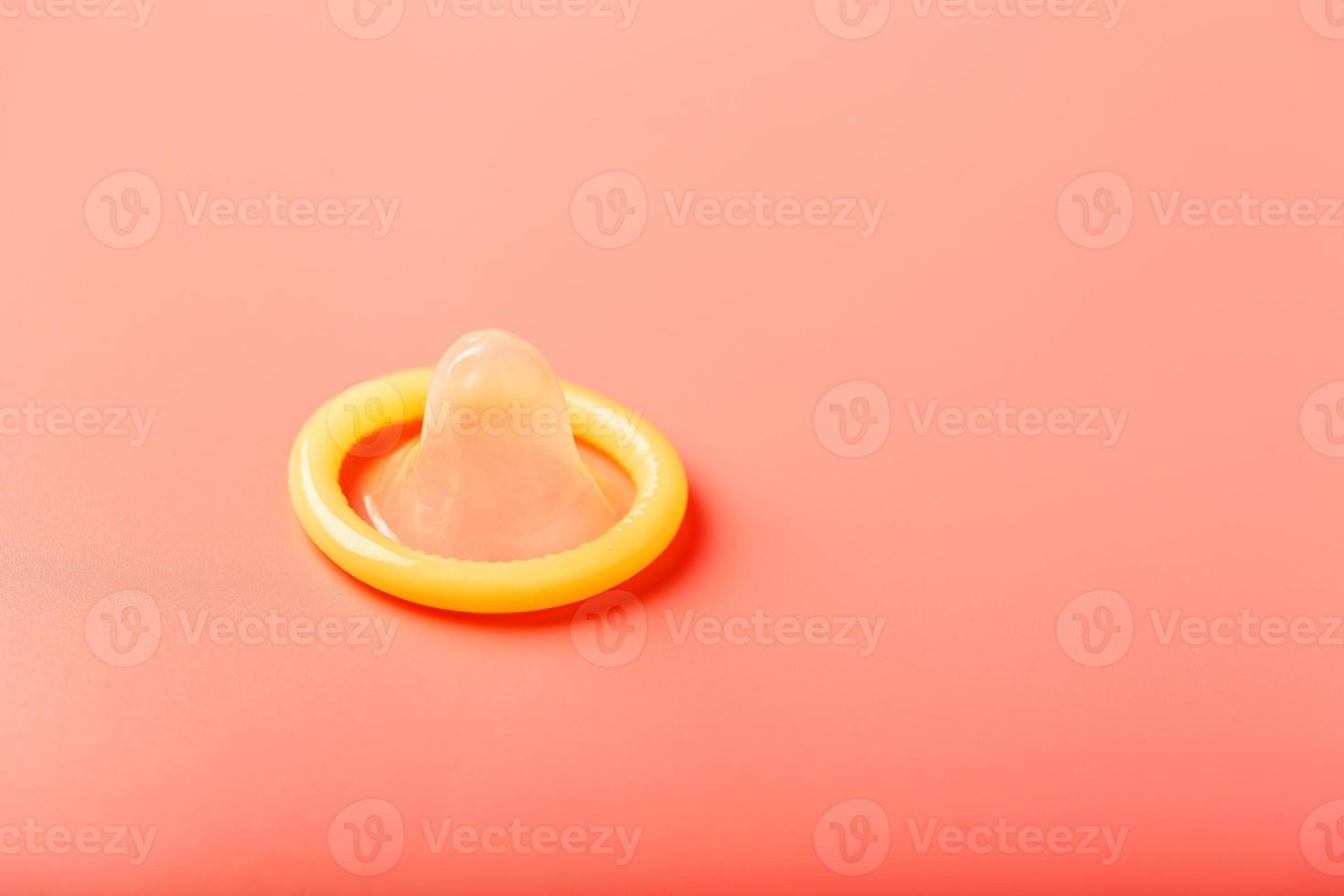 Opened condom on a pink background, close-up, top view. photo