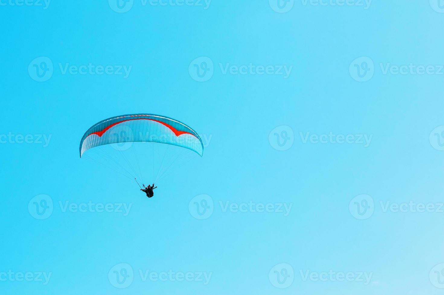 Paraglider soars against the blue sky with clear space. photo