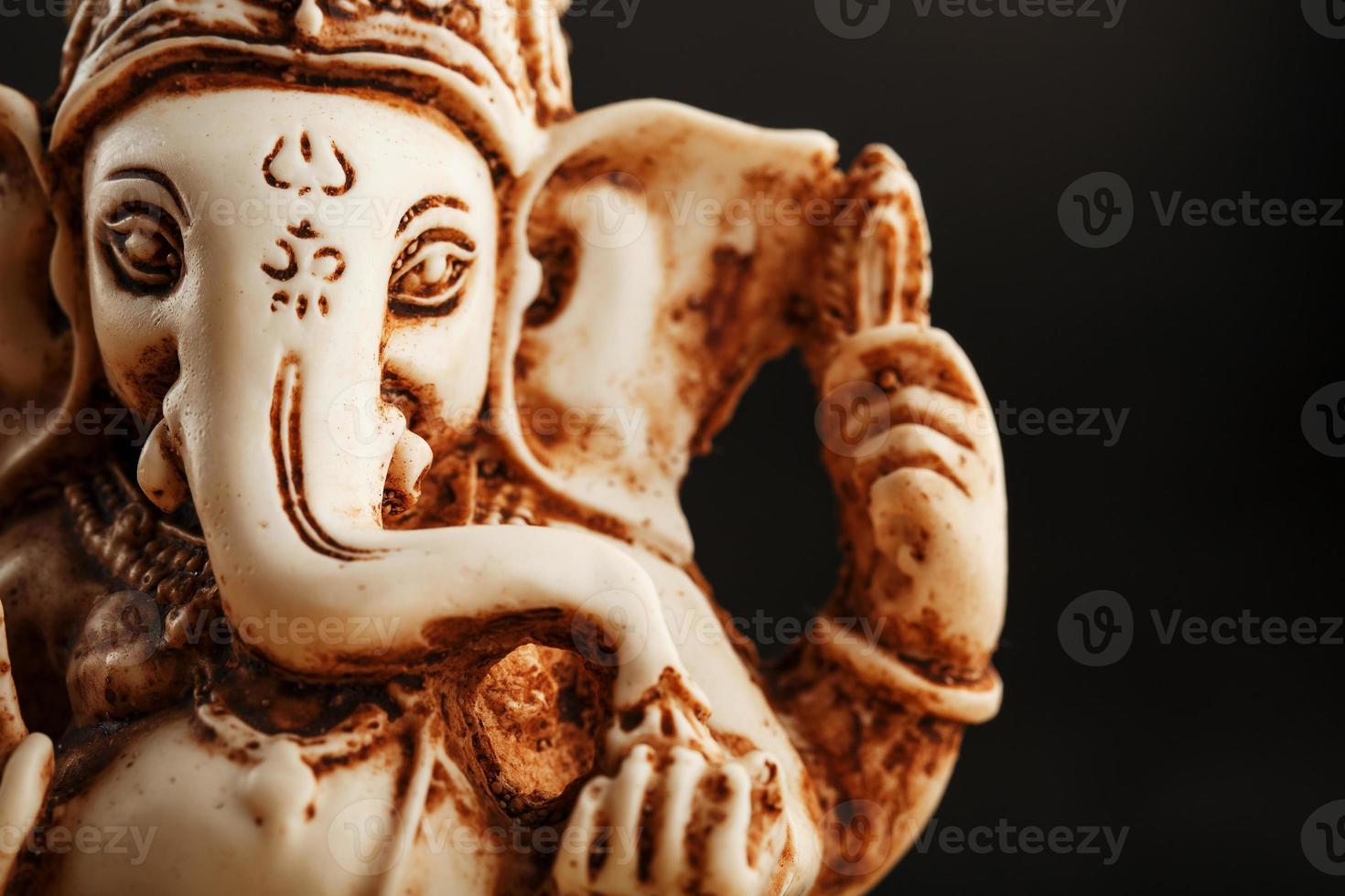 Hindu god Ganesh on a black background. Statue with incense smoke aromo sticks photo